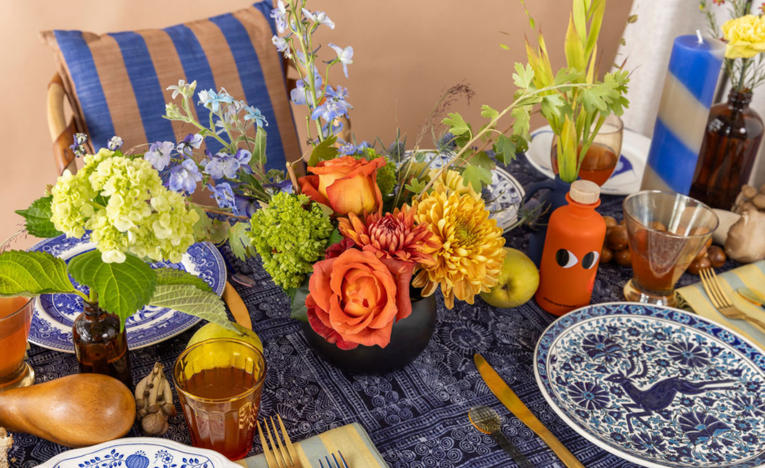 Decorative table setting with flowers, plates, and glasses on a blue tablecloth.